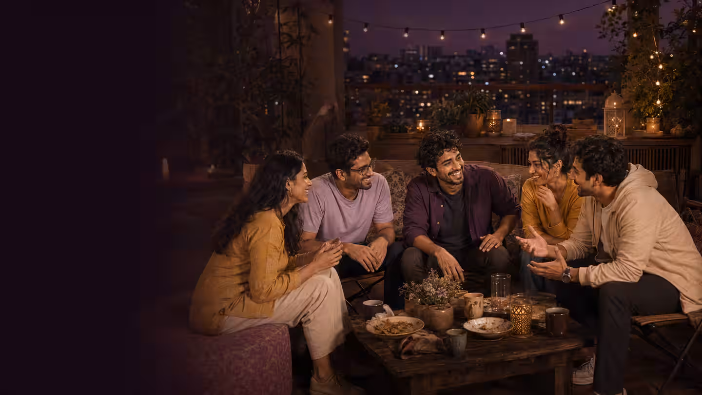 The host relaxed and laughing with close friends after dinner on a Pune terrace.